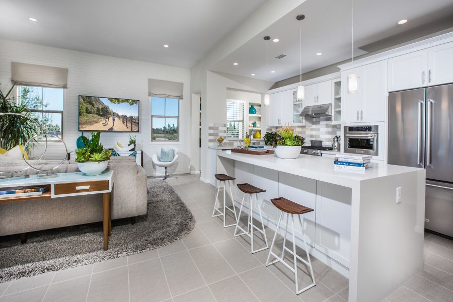 Brightly lit white kitchen with raised shades and a flat-screen TV with an image of runners.