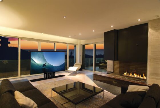 A TV screen rising from the ground in a media room at a home with a view of the ocean.