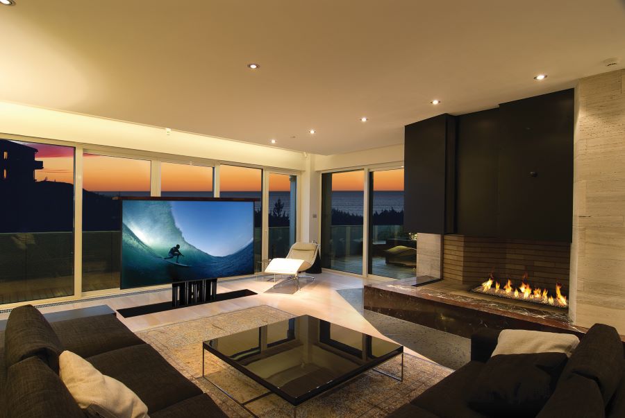 A TV screen rising from the ground in a media room at a home with a view of the ocean.